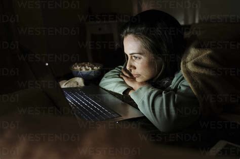 Person streaming a movie on a laptop in a cozy setting